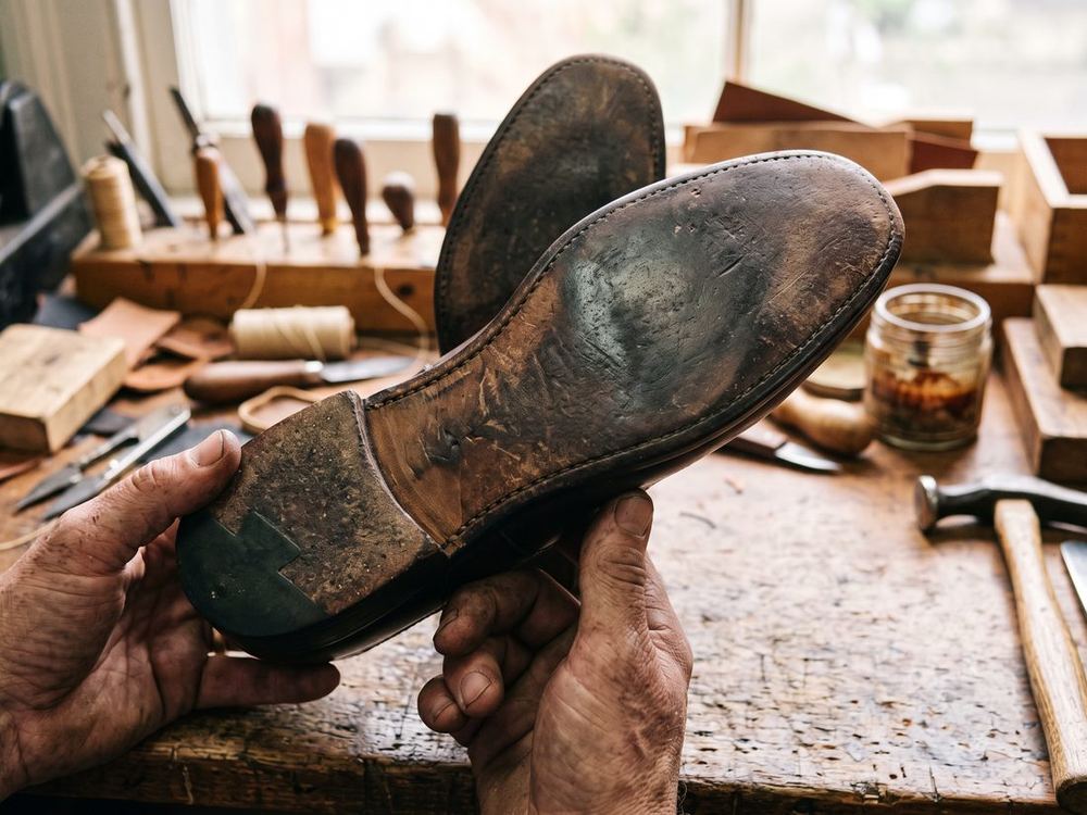 The underside of a brown leather sole, rubbed smooth and shiny across the ball of the foot, with no hole in it.